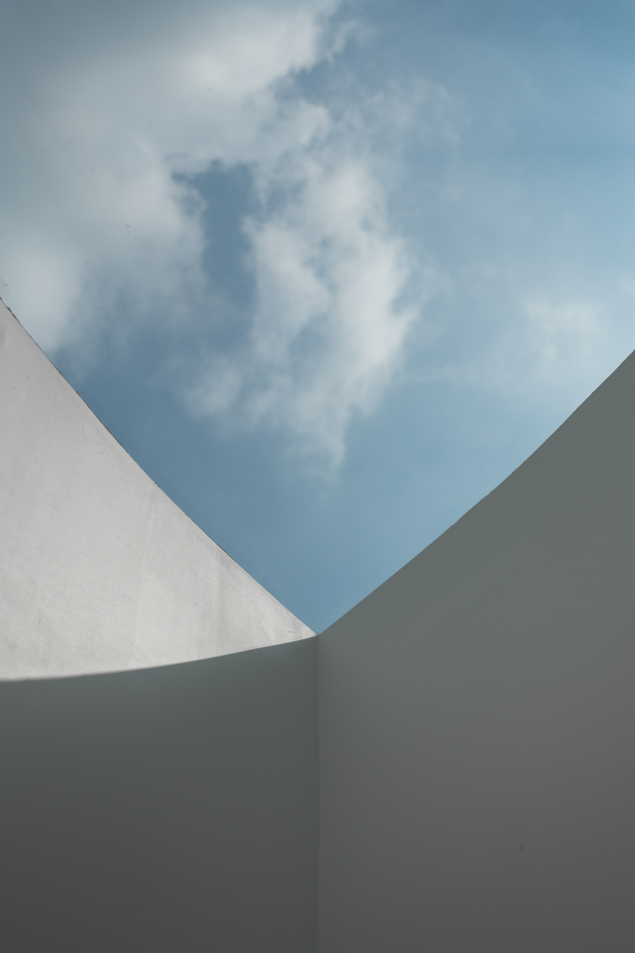 Pale curved walls meeting an open sky
